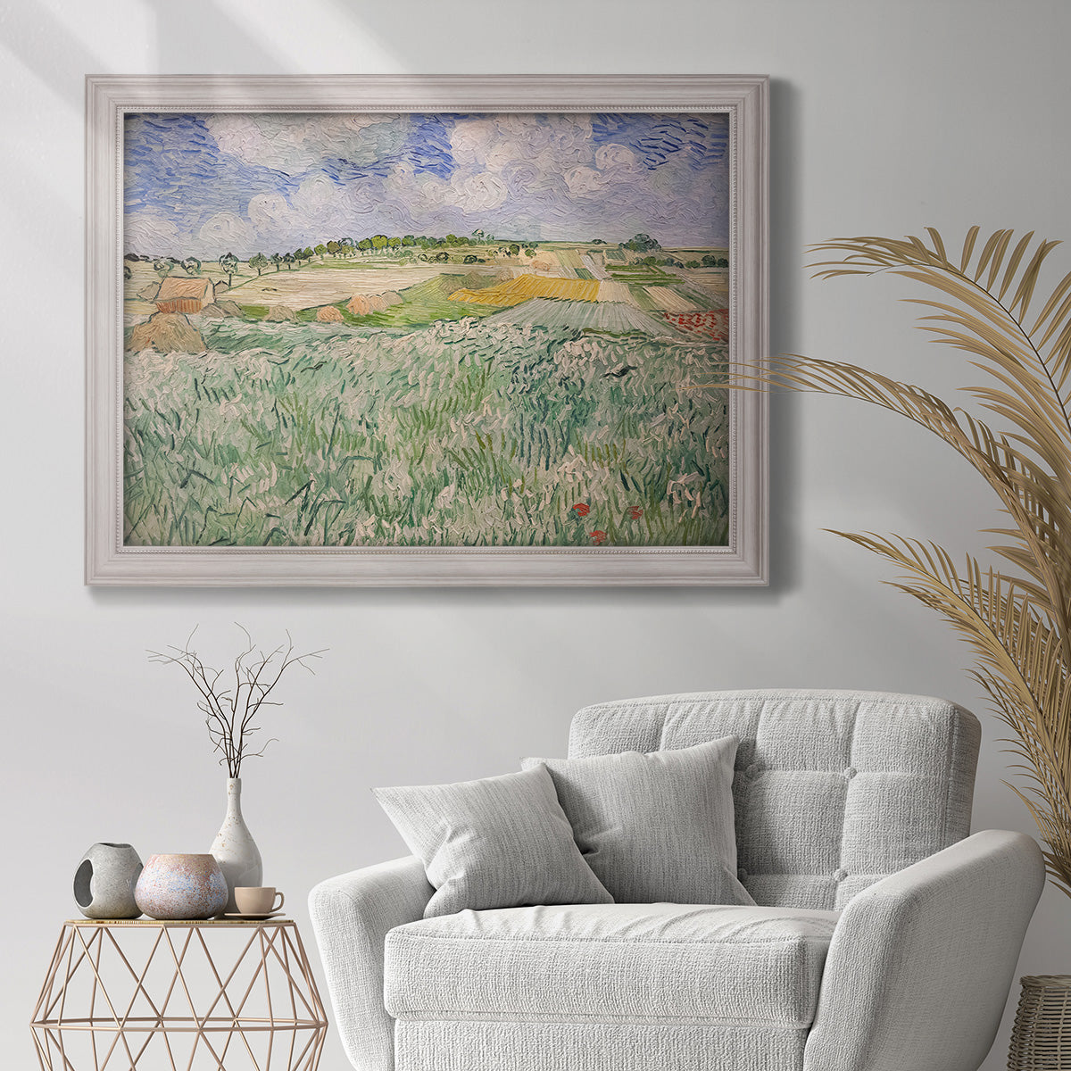 Impressionist countryside landscape near Auvers by Vincent van Gogh in an ornate weathered white frame displayed in a bright interior setting.