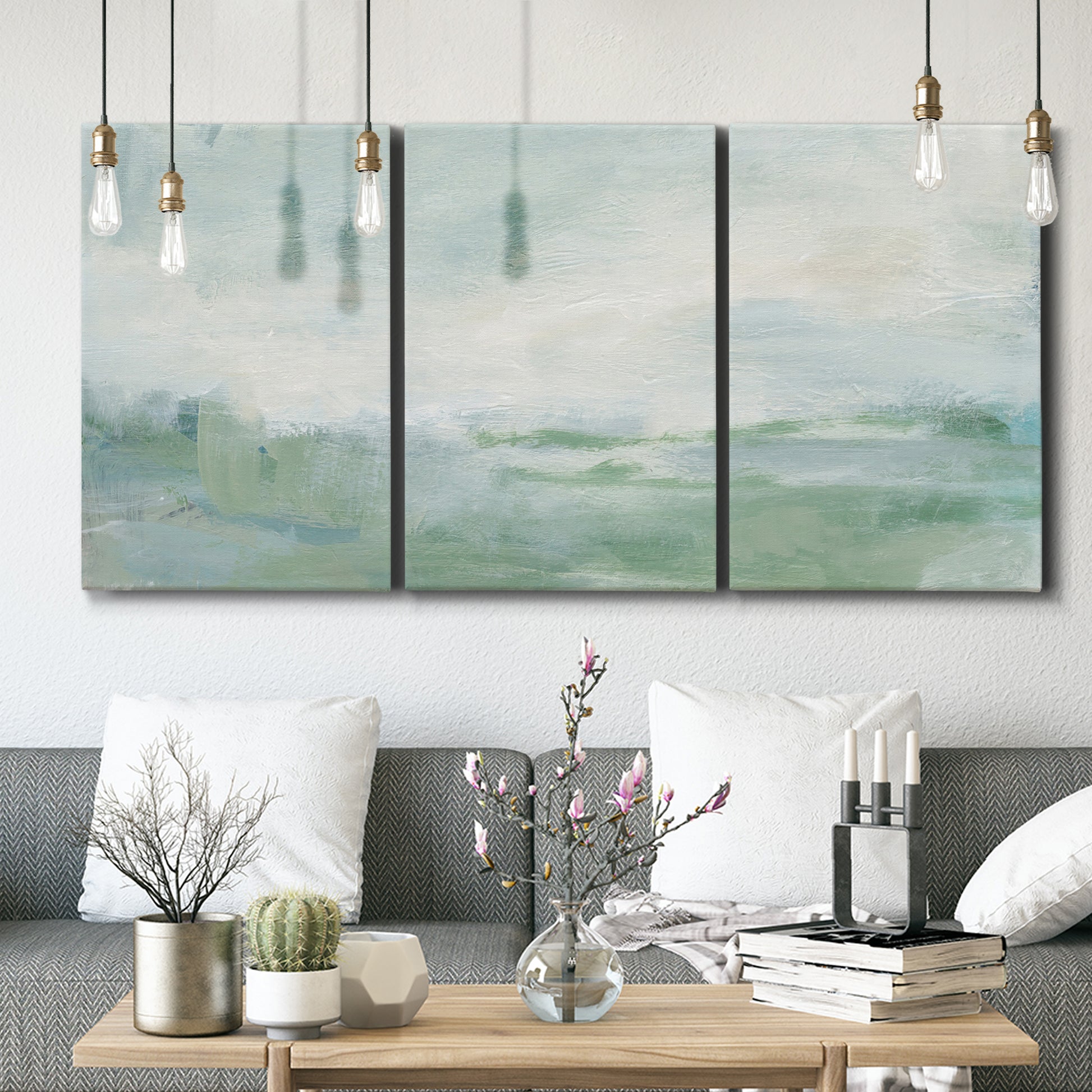 Three-panel canvas wall art featuring soft abstract coastal tones, displayed in a modern living room above seating.