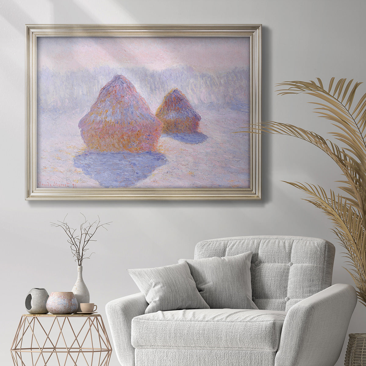 Impressionist winter haystack scene with sunlight by Claude Monet in an ornate champagne frame displayed in a bright interior setting.