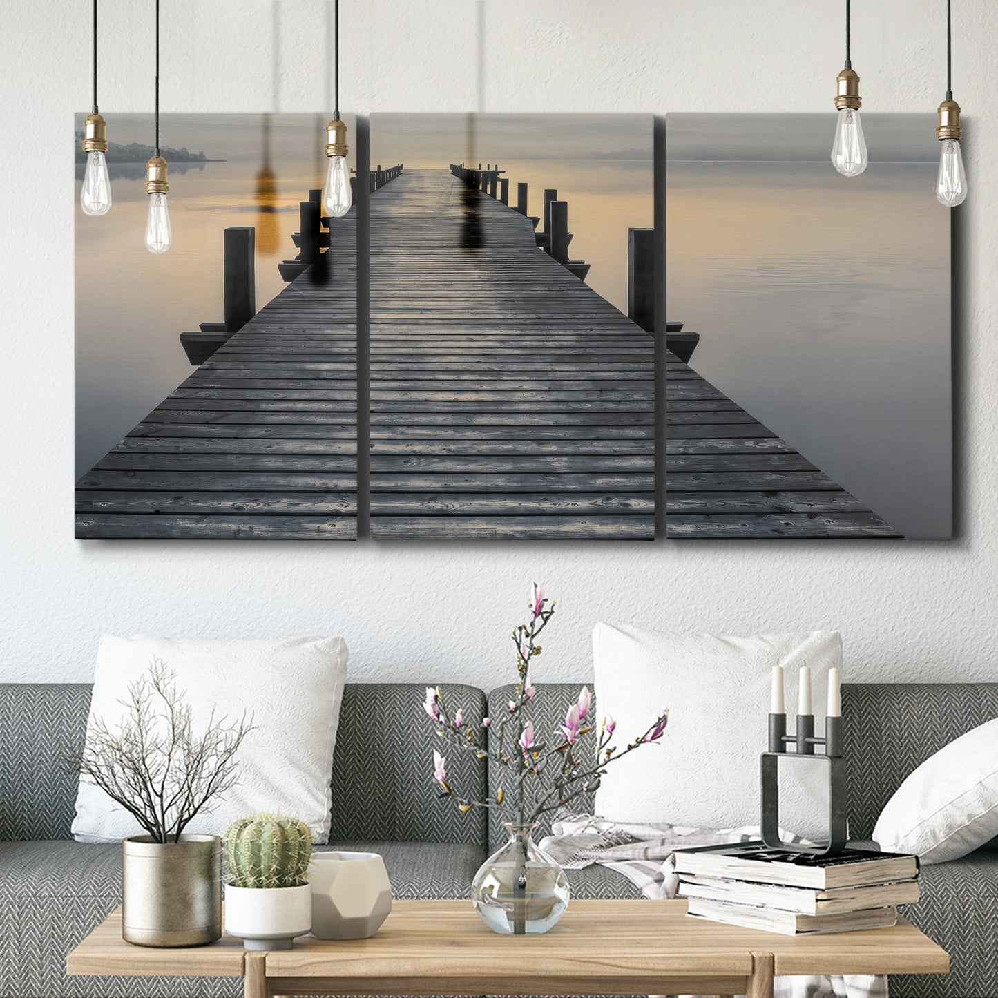 Three-panel canvas wall art featuring sunset over water photograph, displayed in a modern living room above seating.