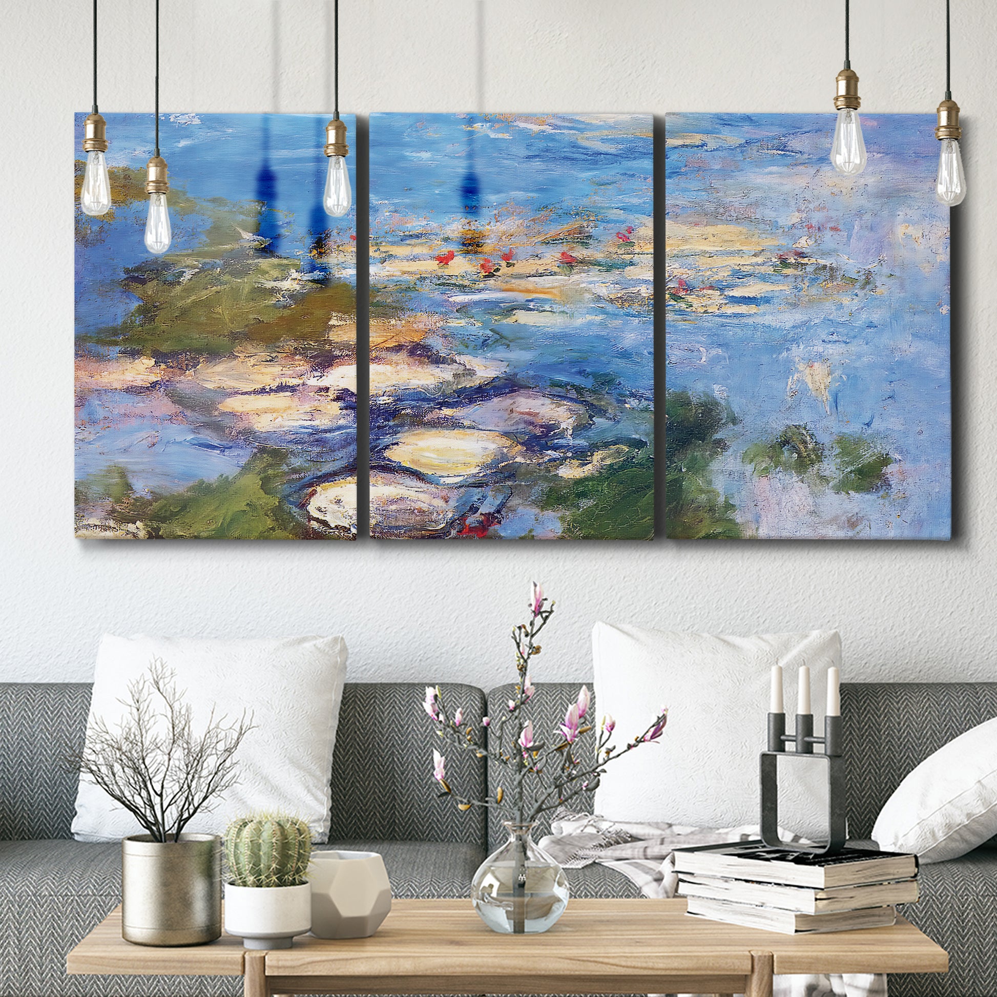 Three-panel canvas wall art featuring water lilies in blue and gold, displayed in a modern living room above seating.