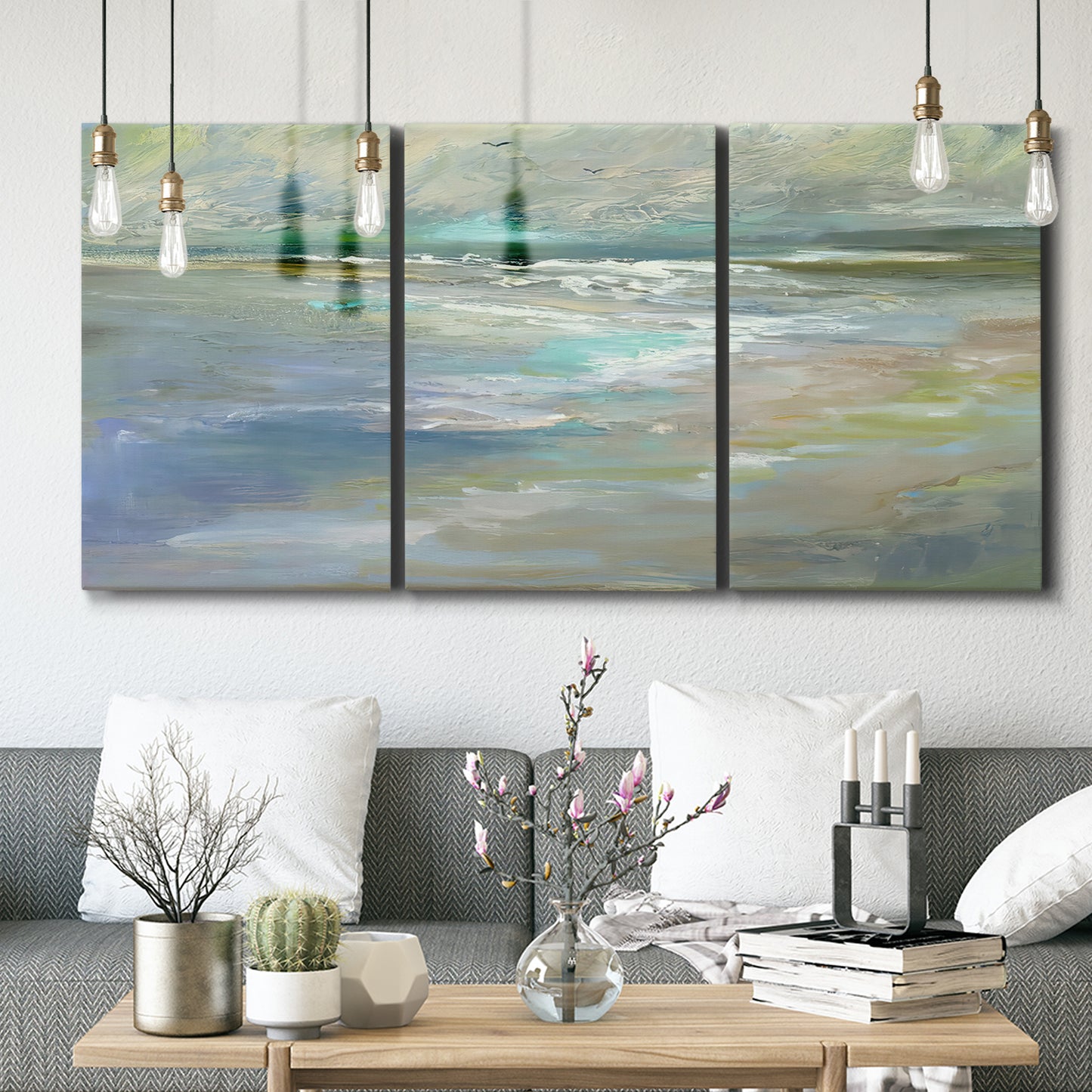 Three-panel canvas wall art featuring soft coastal beach light landscape, displayed in a modern living room above seating.