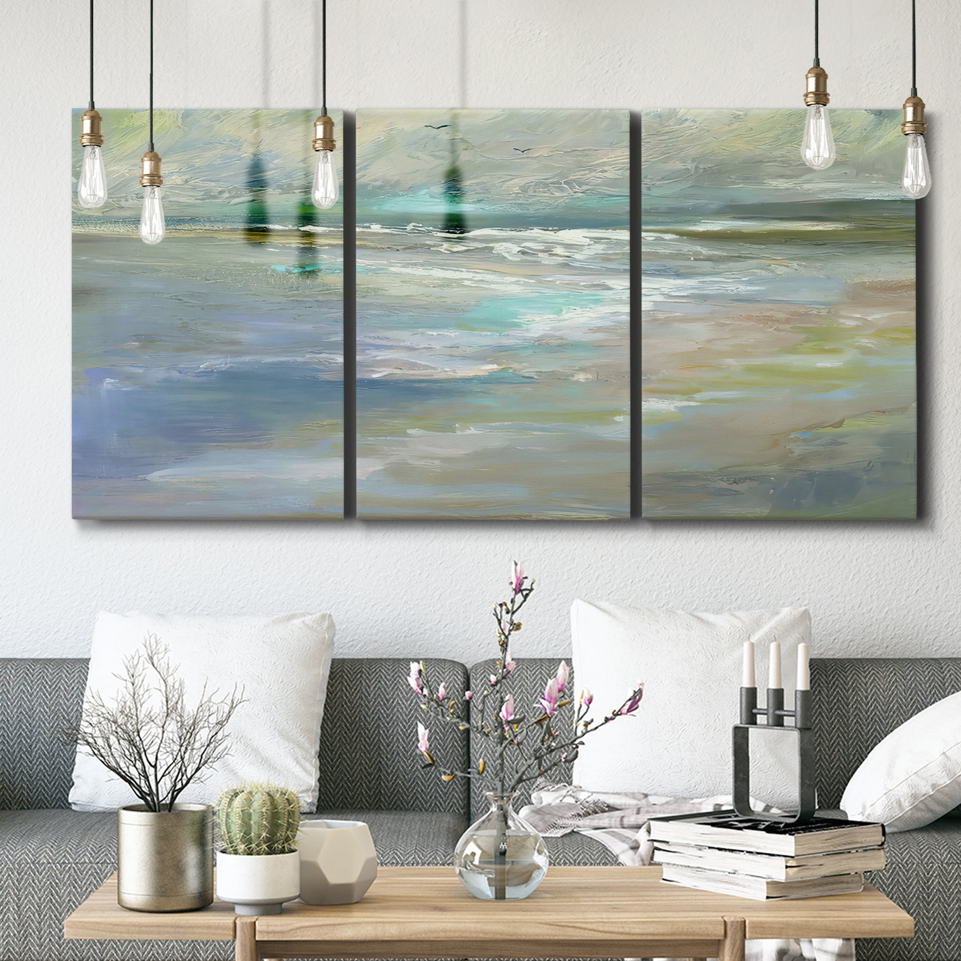 Three-panel canvas wall art featuring soft coastal beach light landscape, displayed in a modern living room above seating.