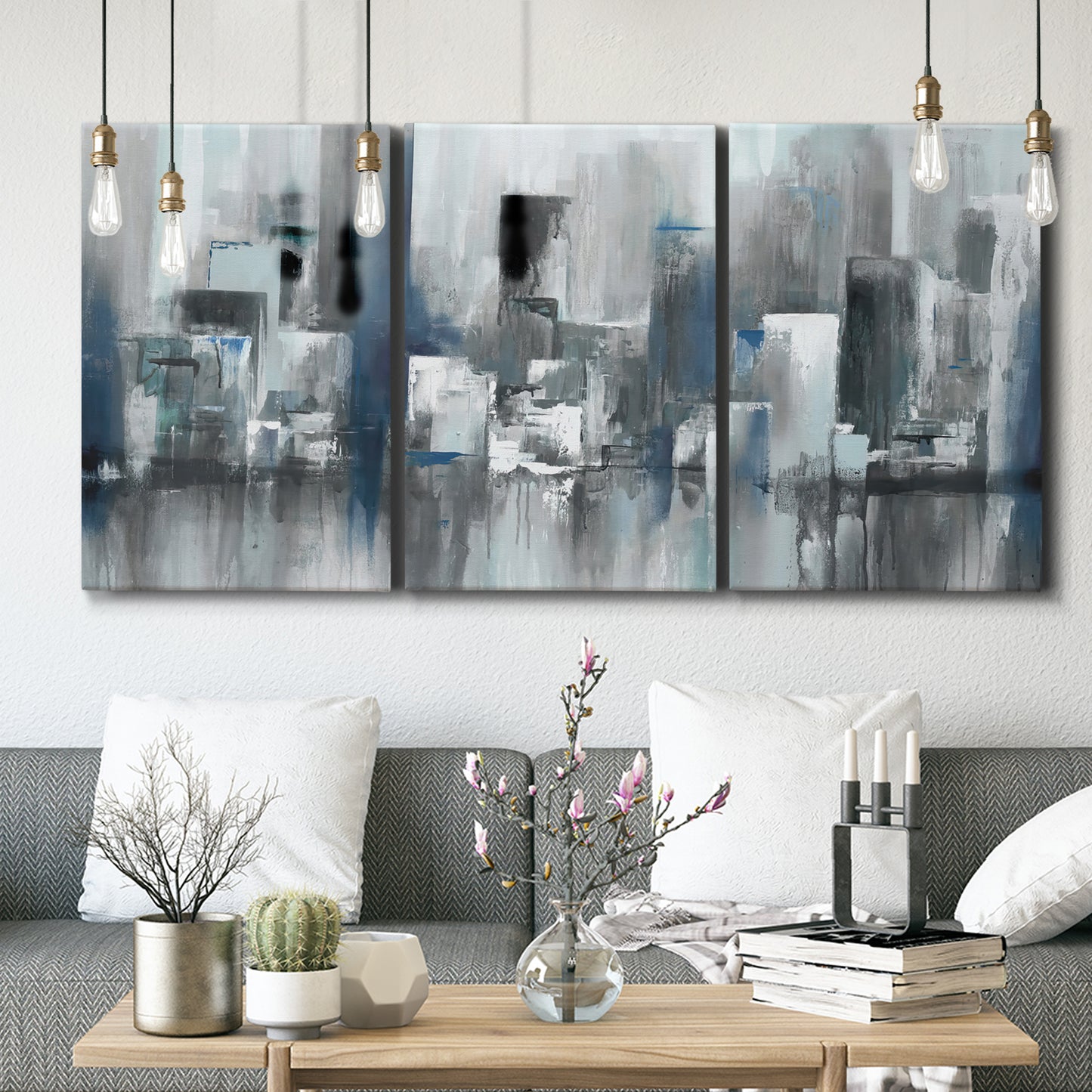 Three-panel canvas wall art featuring urban cityscape rendered in blue tones, displayed in a modern living room above seating.