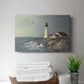 Lighthouse stands tall against crashing waves at a coastal location with birds flying overhead during a calm day