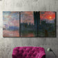 Three-panel canvas wall art featuring parliament silhouetted at dusk, displayed in a living room above a suede accent chair.