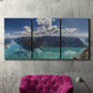 Three-panel canvas wall art featuring tropical water reflections with foliage, displayed in a living room above a suede accent chair.