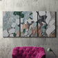 Three-panel canvas wall art featuring layered canyon inspired abstract forms, displayed in a living room above a suede accent chair.
