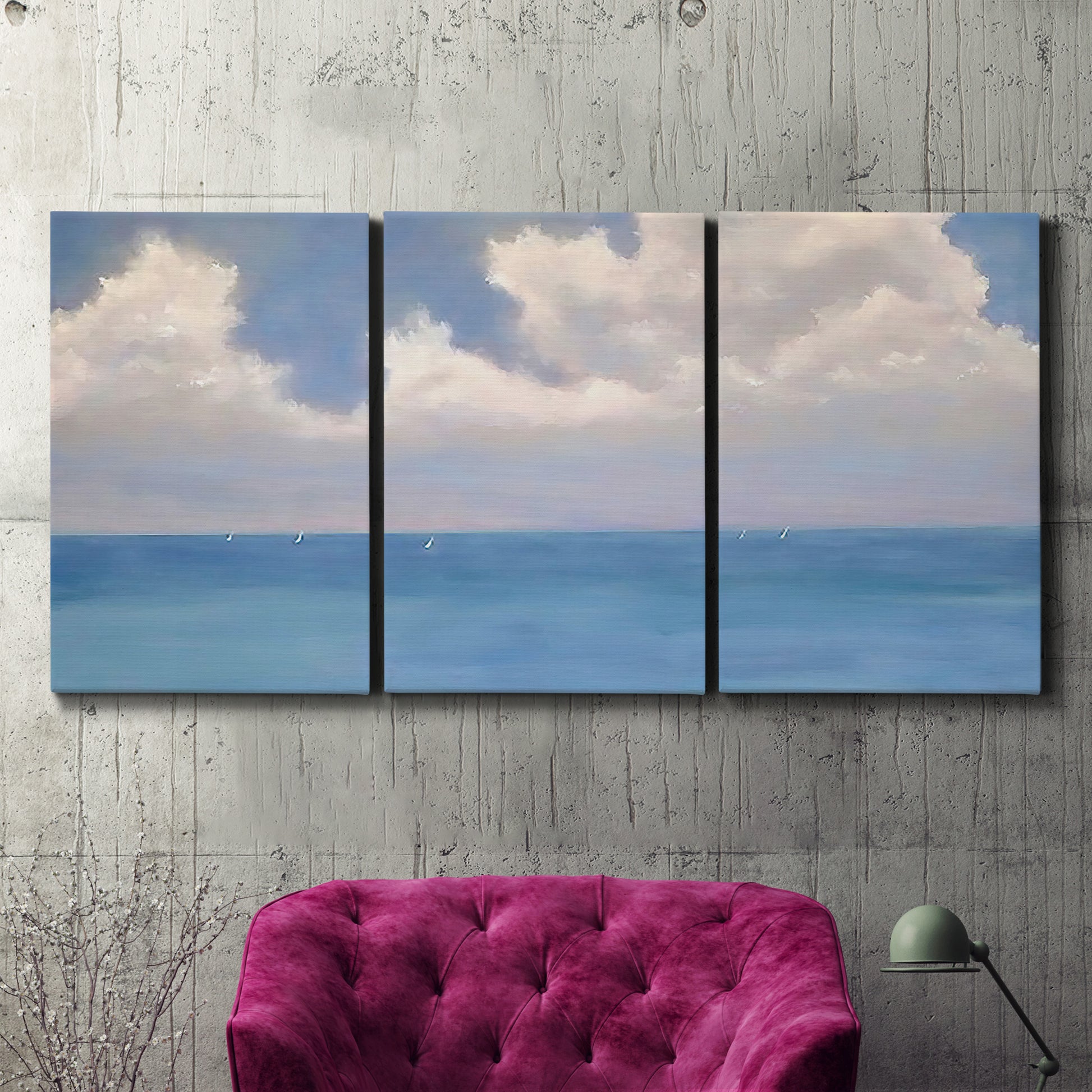 Three-panel canvas wall art featuring coastal shoreline with distant horizon, displayed in a living room above a suede accent chair.