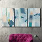 Three-panel canvas wall art featuring layered geometric abstract strata forms, displayed in a living room above a suede accent chair.