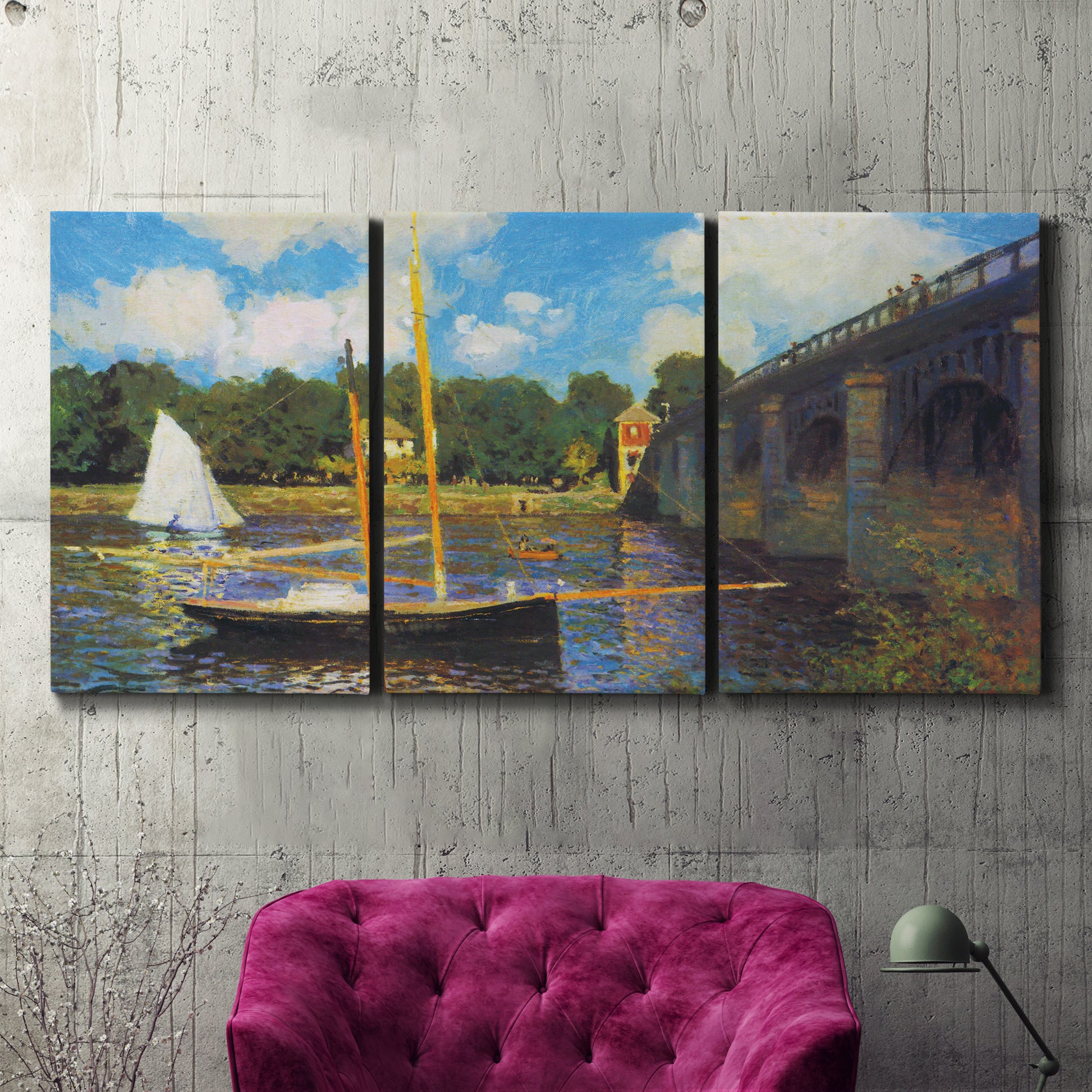 Three-panel canvas wall art featuring bridge crossing river landscape, displayed in a living room above a suede accent chair.