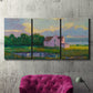 Three-panel canvas wall art featuring farmhouse near coastline landscape, displayed in a living room above a suede accent chair.