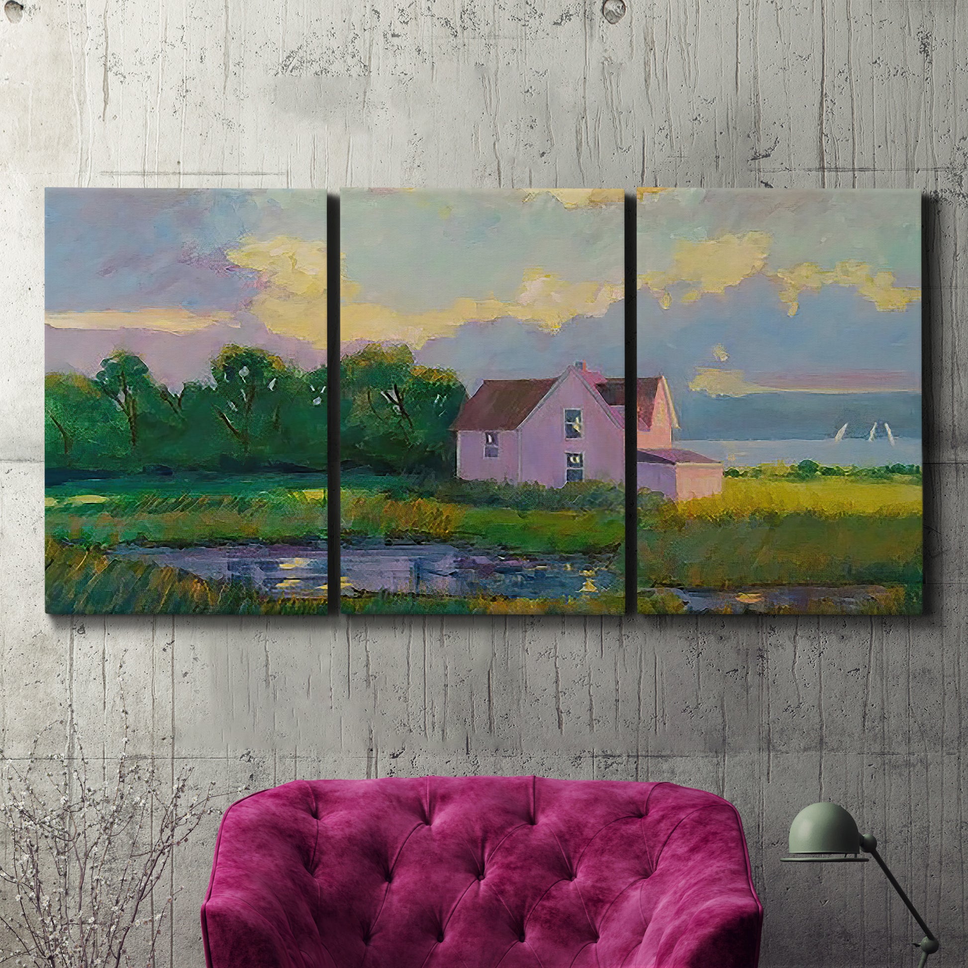 Three-panel canvas wall art featuring farmhouse near coastline landscape, displayed in a living room above a suede accent chair.
