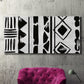 Three-panel canvas wall art featuring geometric abstract forms merging pattern, displayed in a living room above a suede accent chair.