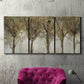 Three-panel canvas wall art featuring sunlight filtering through trees, displayed in a living room above a suede accent chair.