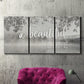 Three-panel canvas wall art featuring uplifting life themed typography, displayed in a living room above a suede accent chair.