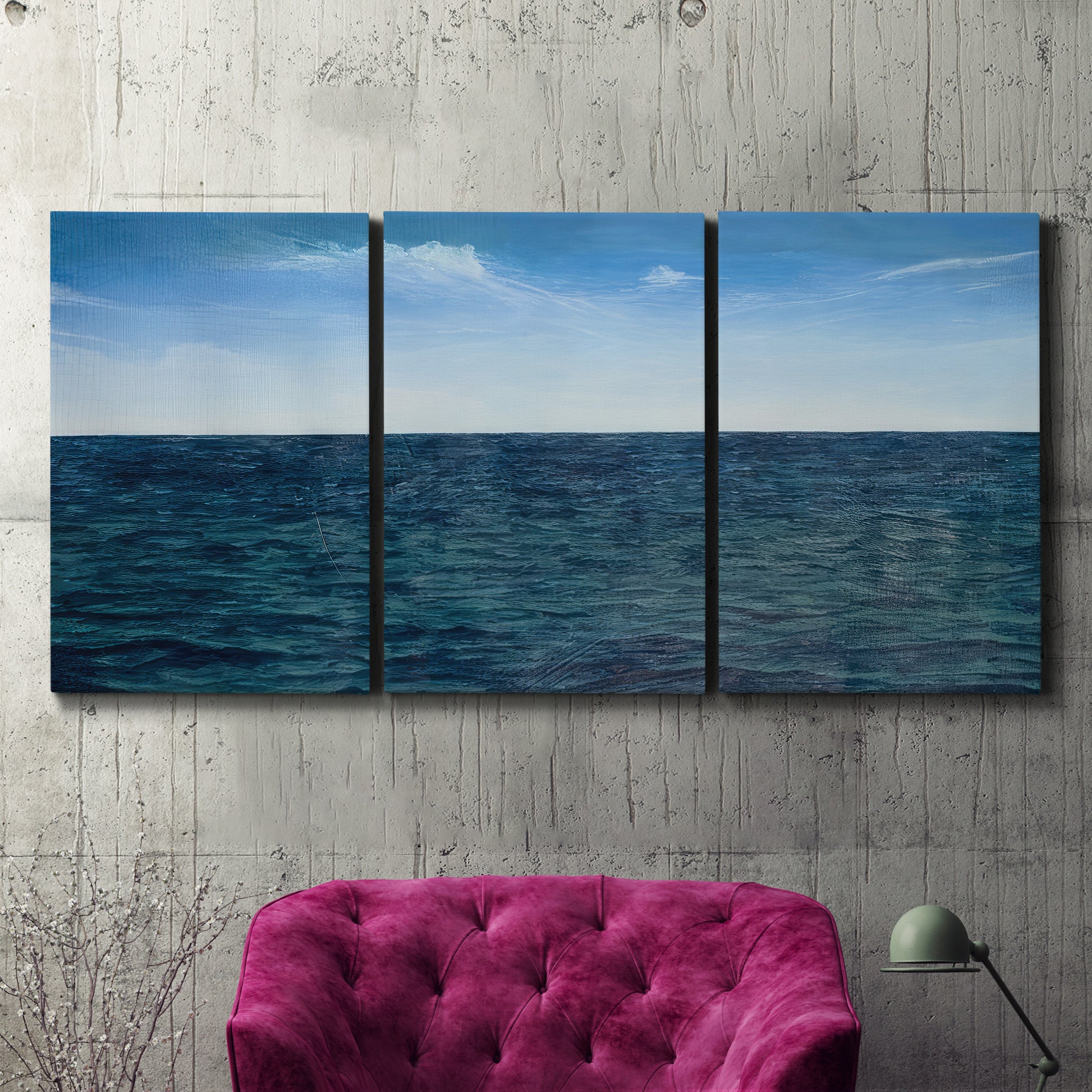 Three-panel canvas wall art featuring open water landscape with wide horizon, displayed in a living room above a suede accent chair.