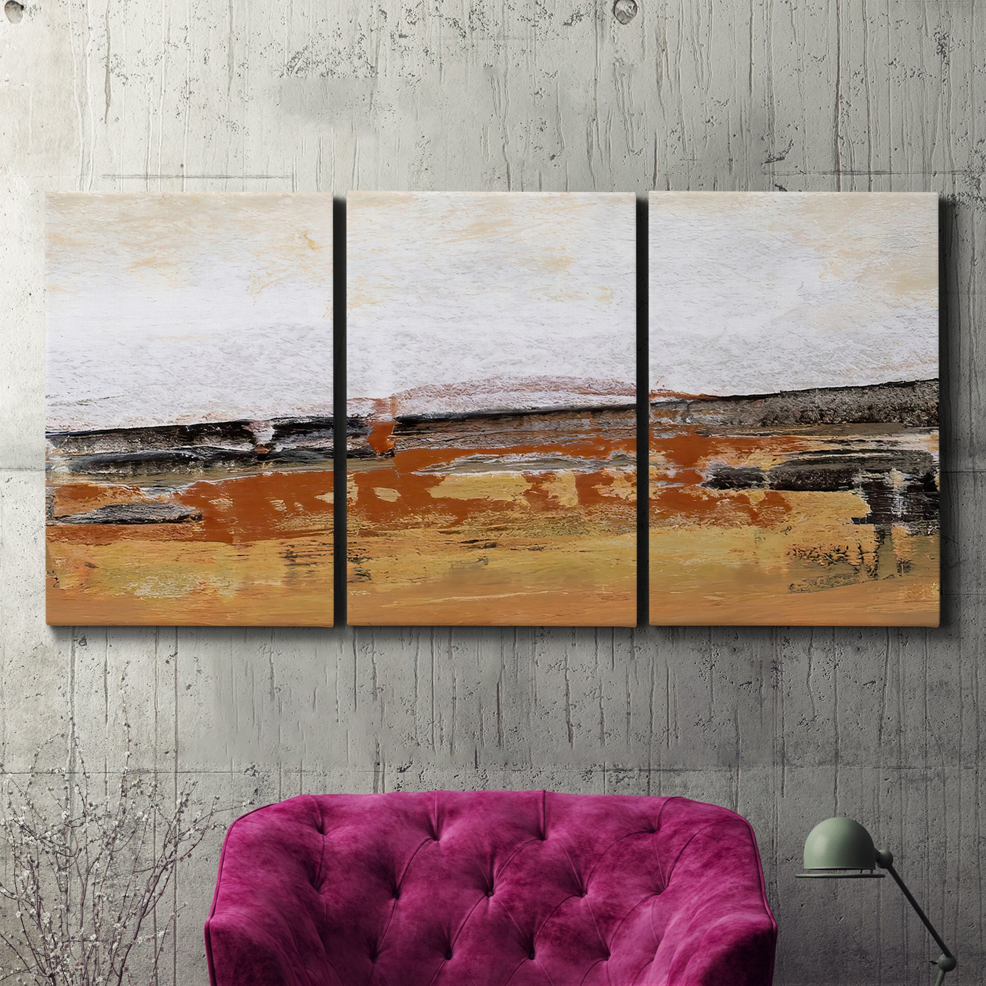 Three-panel canvas wall art featuring abstract bridge landscape in ochre, displayed in a living room above a suede accent chair.