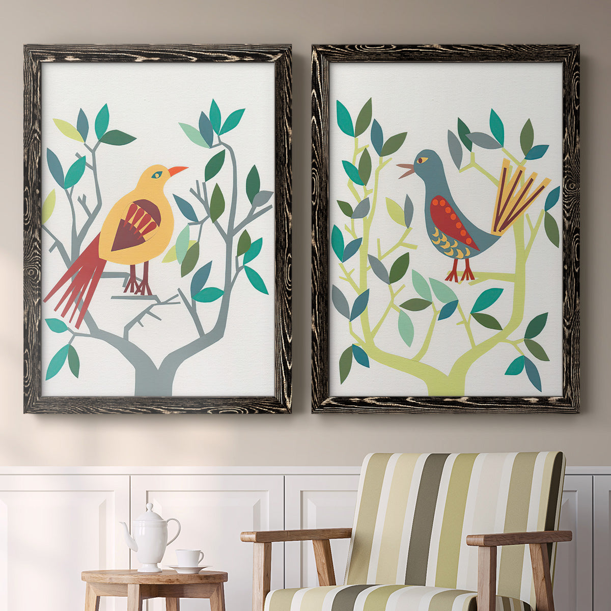 Set of two black barnwood framed canvas prints depicting two modern folk-art bird illustrations featuring stylized colorful birds perched among leafy branches above a sideboard in a cozy sitting room.