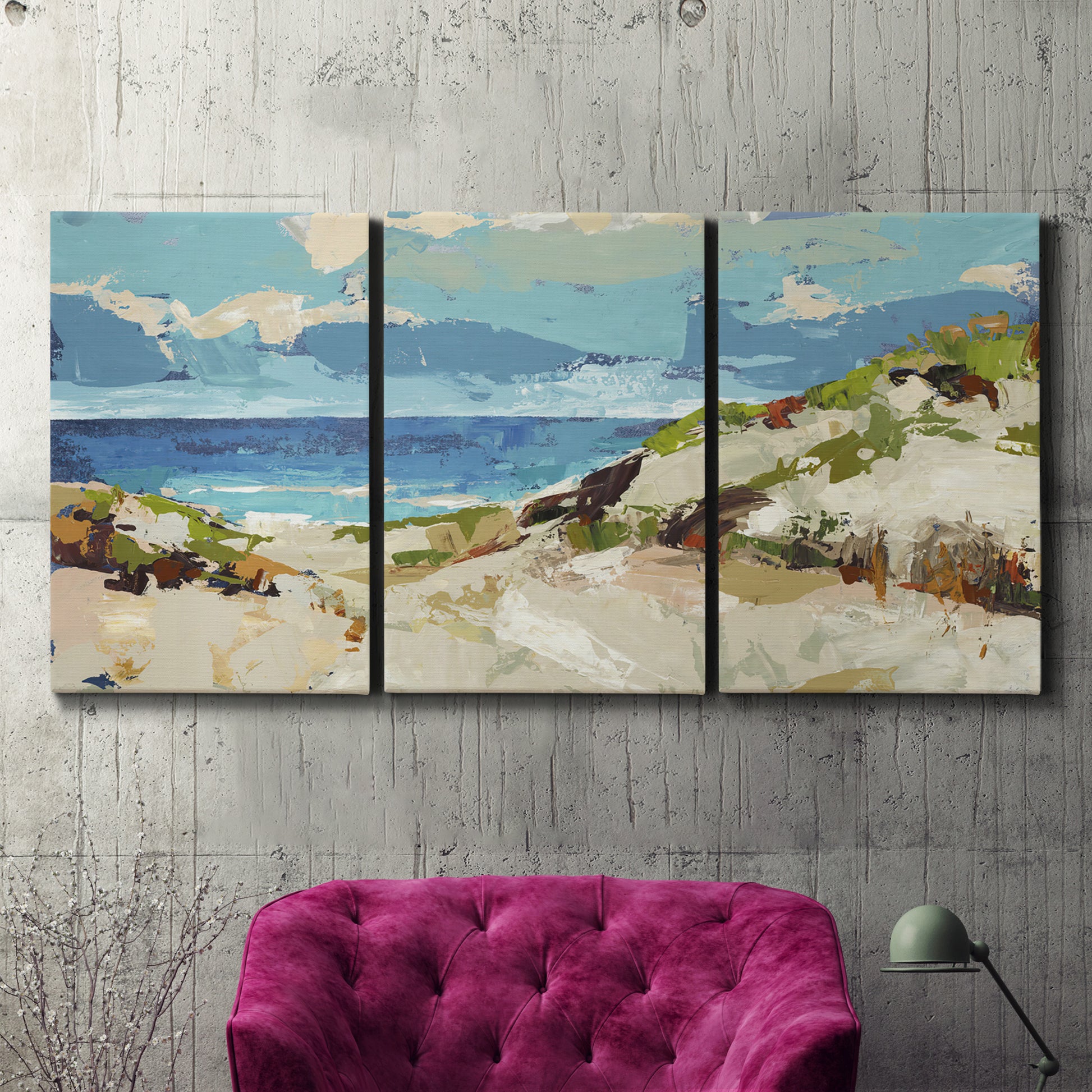Three-panel canvas wall art featuring sand dunes beside open water, displayed in a living room above a suede accent chair.