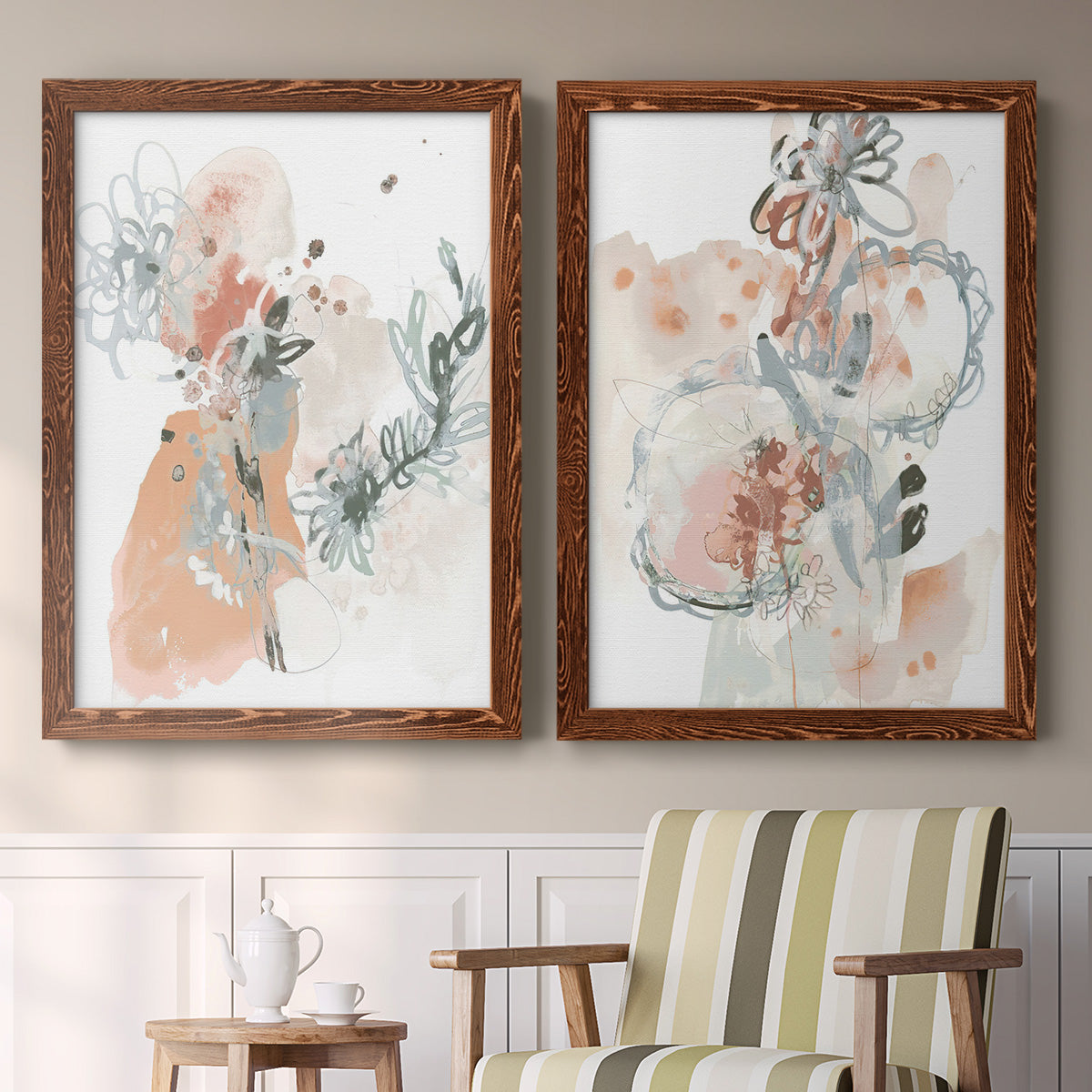 Set of two maple barnwood framed canvas prints depicting two abstract watercolor botanicals featuring loose blush gray and coral floral gestures above a sideboard in a cozy sitting room.