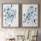 Set of two gray barnwood framed canvas prints depicting two expressive watercolor botanical paintings featuring loose blue flowers and leafy branches above a sideboard in a cozy sitting room.