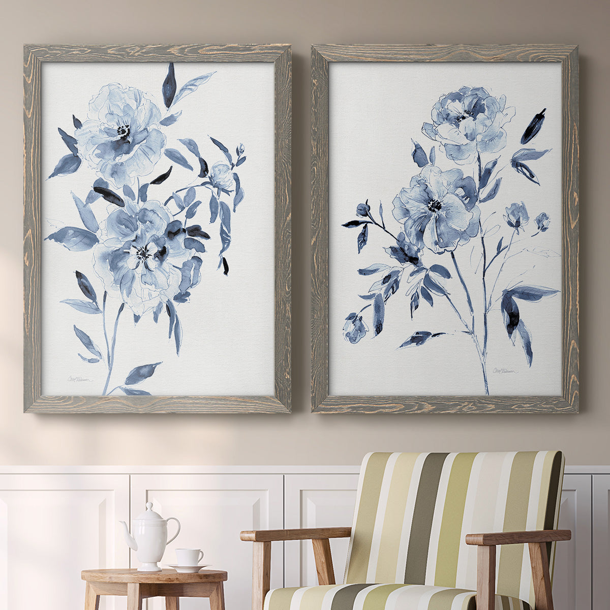 Set of two gray barnwood framed canvas prints depicting two expressive watercolor botanical paintings featuring loose blue flowers and leafy branches above a sideboard in a cozy sitting room.