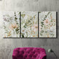 Three-panel canvas wall art featuring vintage floral botanical sketchbook, displayed in a living room above a suede accent chair.