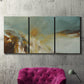 Three-panel canvas wall art featuring earth toned abstract solar landscape, displayed in a living room above a suede accent chair.