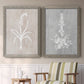Set of two gray barnwood framed canvas prints depicting two rustic minimalist botanical prints featuring white botanical silhouettes on softly weathered neutral backgrounds above a sideboard in a cozy sitting room.
