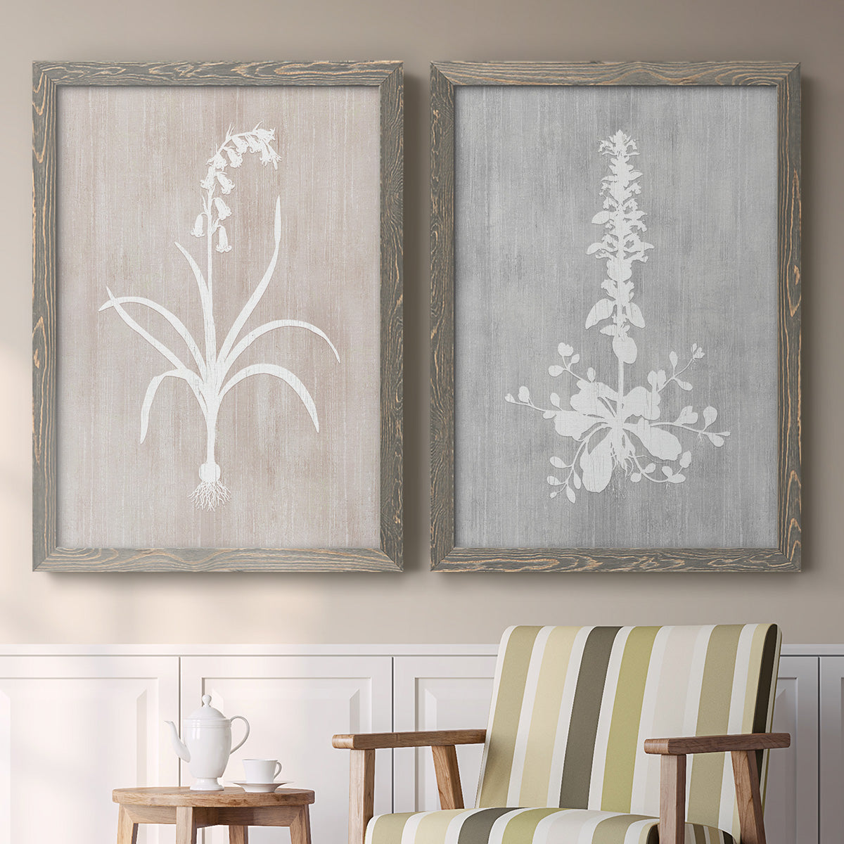 Set of two gray barnwood framed canvas prints depicting two rustic minimalist botanical prints featuring white botanical silhouettes on softly weathered neutral backgrounds above a sideboard in a cozy sitting room.