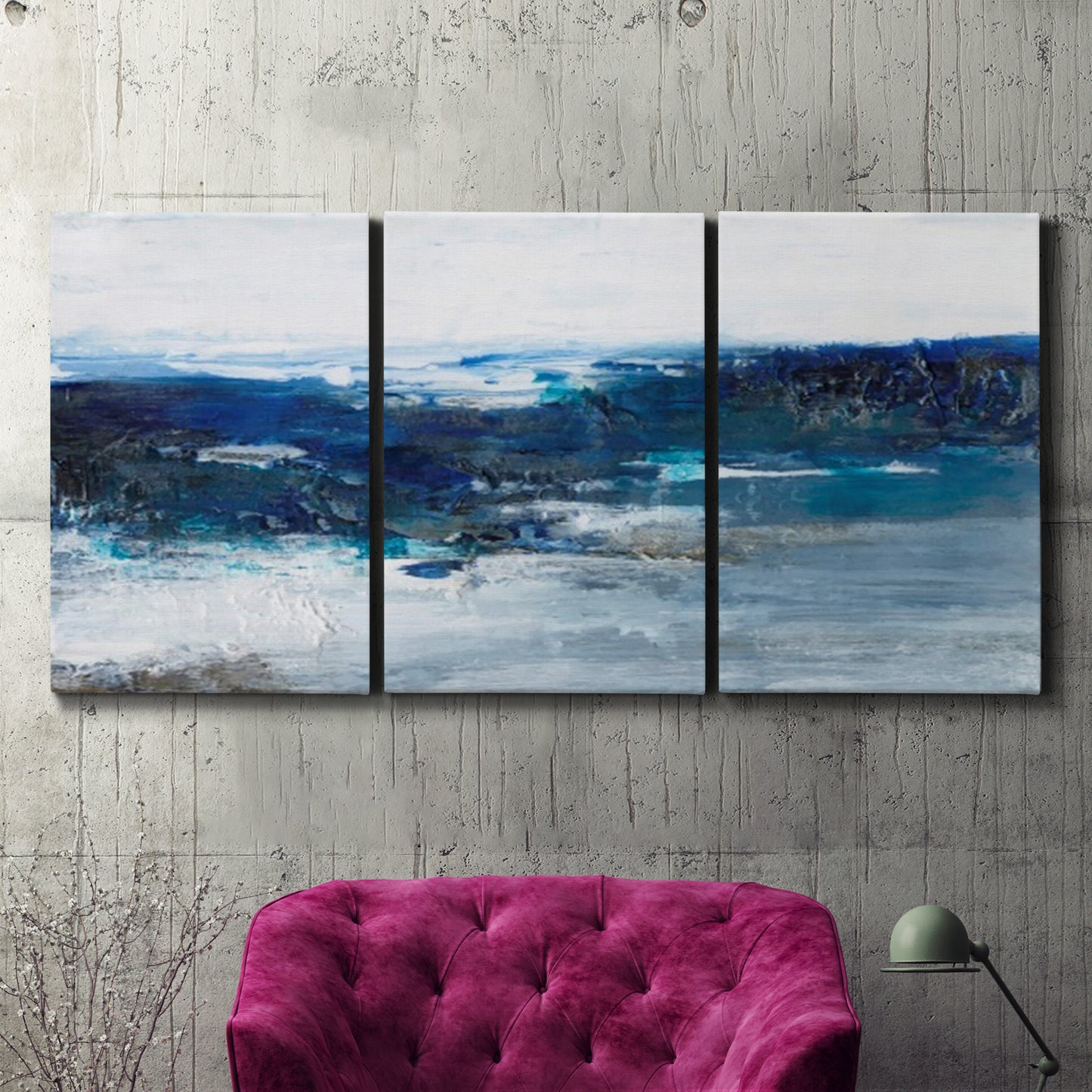 Three-panel canvas wall art featuring moody abstract sea with depth, displayed in a living room above a suede accent chair.