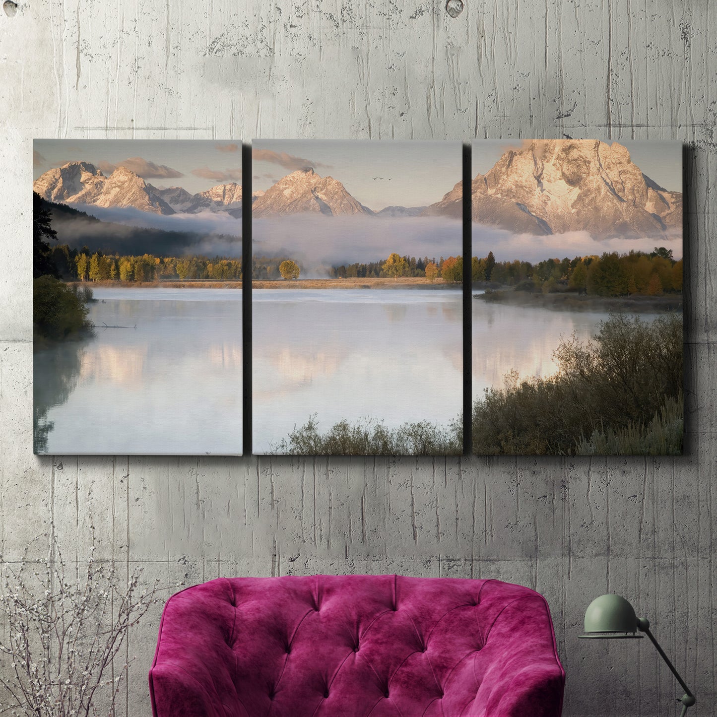 Three-panel canvas wall art featuring fog drifting over winding river, displayed in a living room above a suede accent chair.