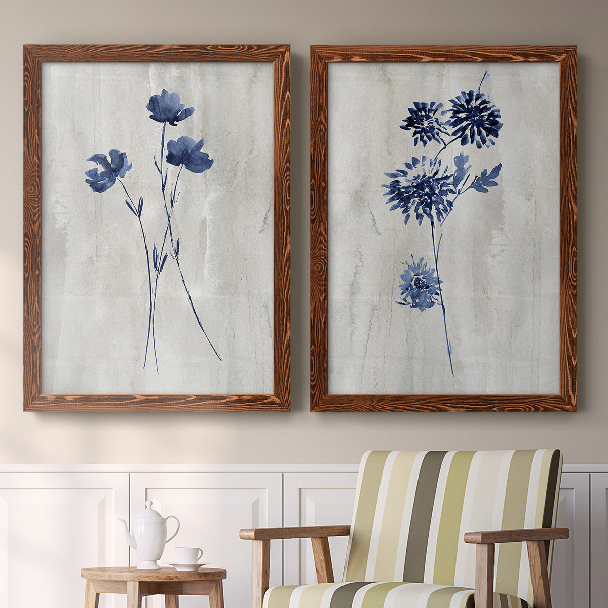 Set of two maple barnwood framed canvas prints depicting two rustic monochrome botanical paintings featuring blue wildflower stems on weathered neutral paper above a sideboard in a cozy sitting room.