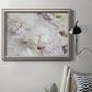 White peonies in bloom in an ornate vintage silver frame displayed in a neutral interior setting.