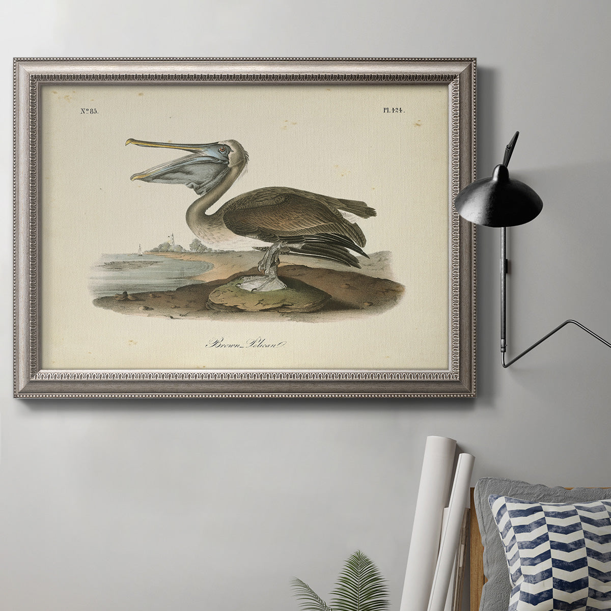 Antique brown pelican bird illustration by John James Audubon in an ornate vintage silver frame displayed in a neutral interior setting.