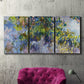 Three-panel canvas wall art featuring cascading purple wisteria blooms, displayed in a living room above a suede accent chair.