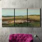 Three-panel canvas wall art featuring pastoral landscape with winding road, displayed in a living room above a suede accent chair.