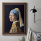 Iconic portrait of a girl wearing a pearl earring by Johannes Vermeer in an ornate bronzed mahogany wood frame displayed in a neutral interior setting.