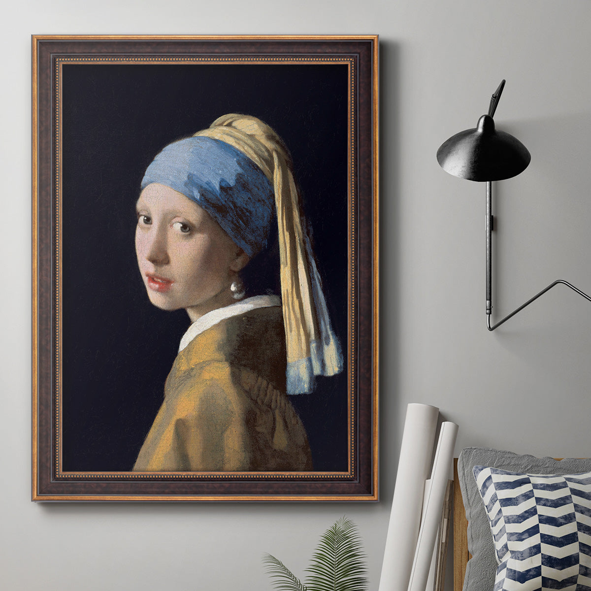 Iconic portrait of a girl wearing a pearl earring by Johannes Vermeer in an ornate bronzed mahogany wood frame displayed in a neutral interior setting.