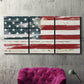 Three-panel canvas wall art featuring rustic american flag country style, displayed in a living room above a suede accent chair.