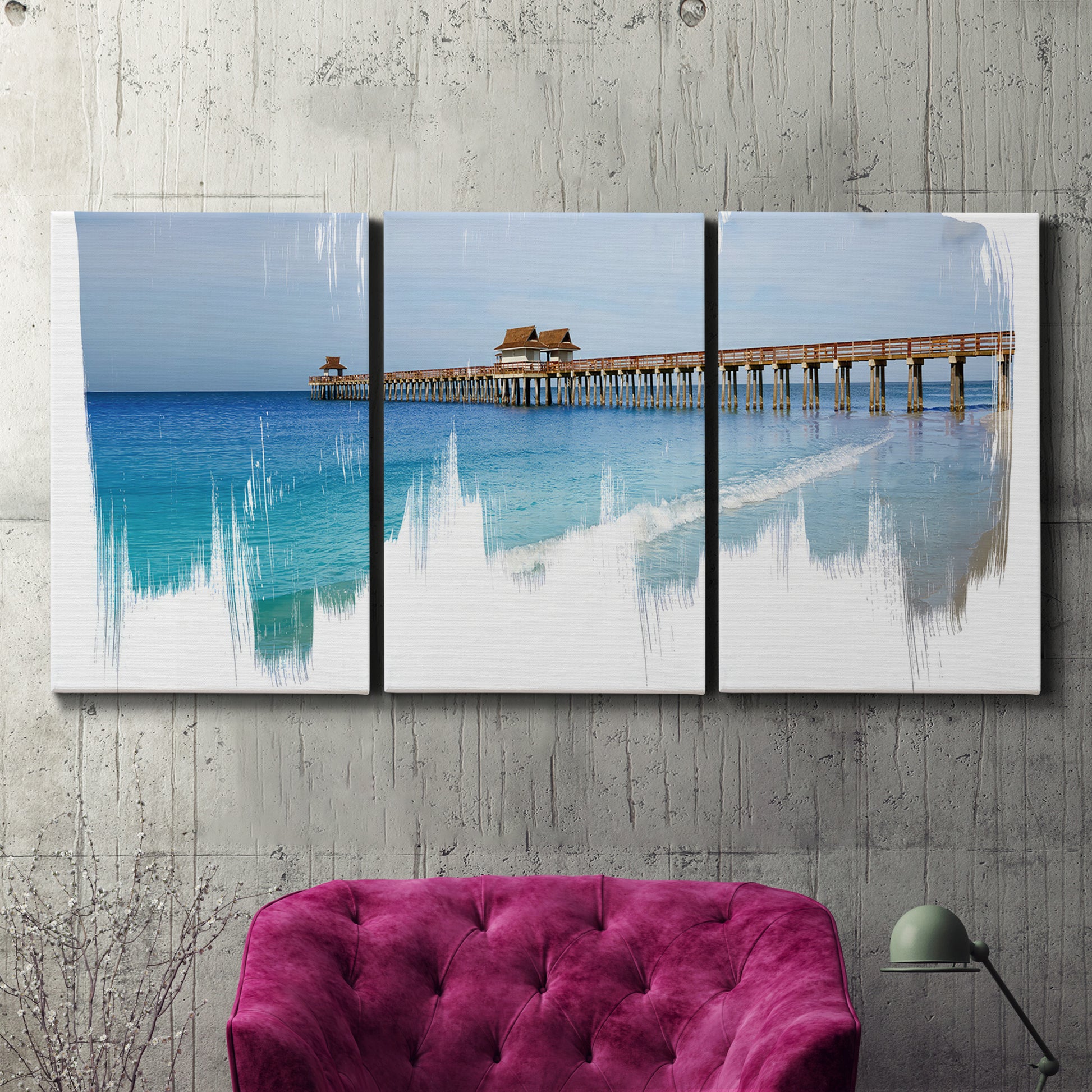 Three-panel canvas wall art featuring coastal pier extending over water, displayed in a living room above a suede accent chair.