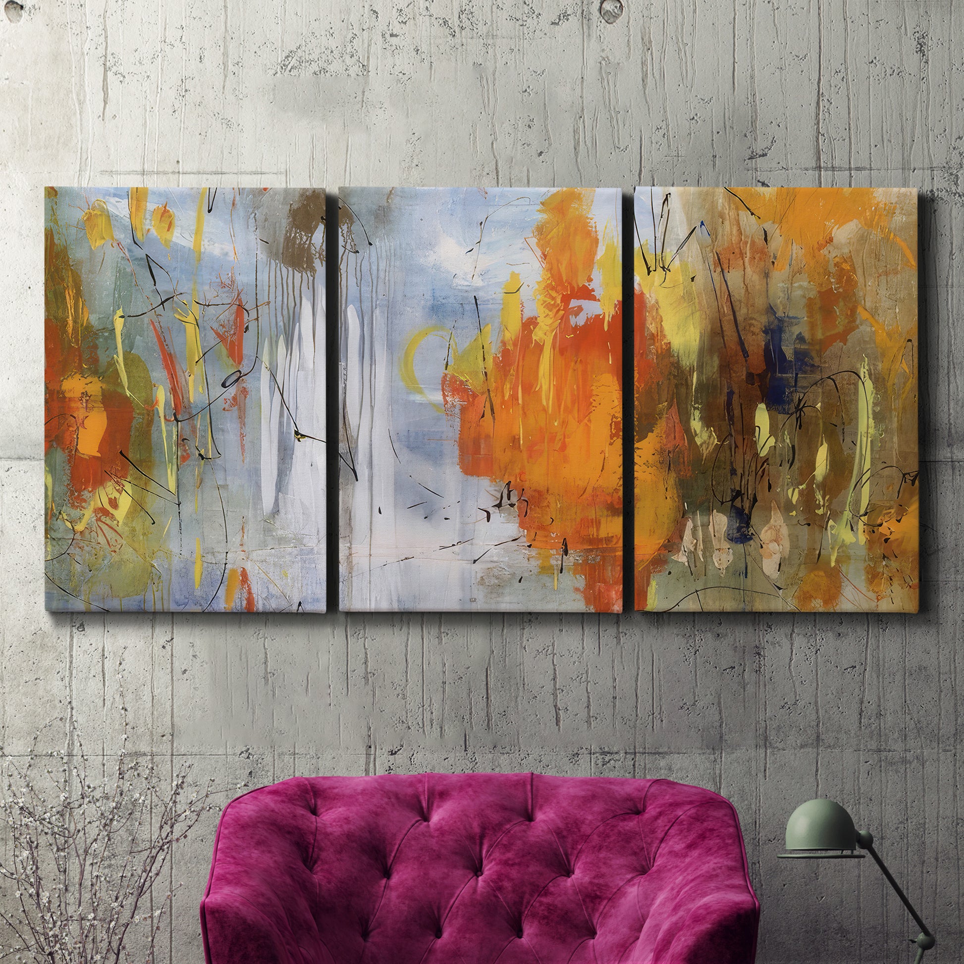 Three-panel canvas wall art featuring abstract warm sunset tones, displayed in a living room above a suede accent chair.