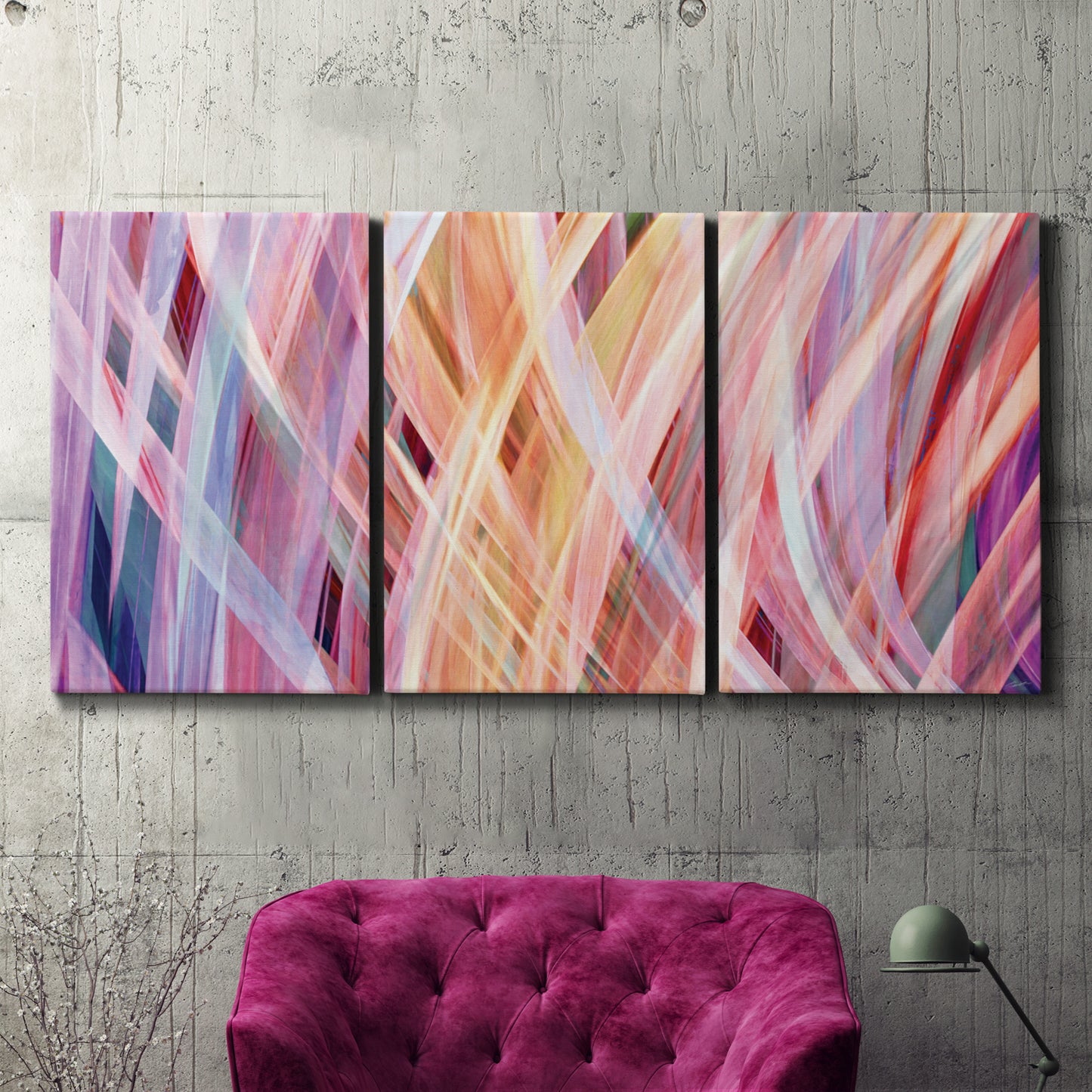 Three-panel canvas wall art featuring layered modern abstract color ribbons, displayed in a living room above a suede accent chair.