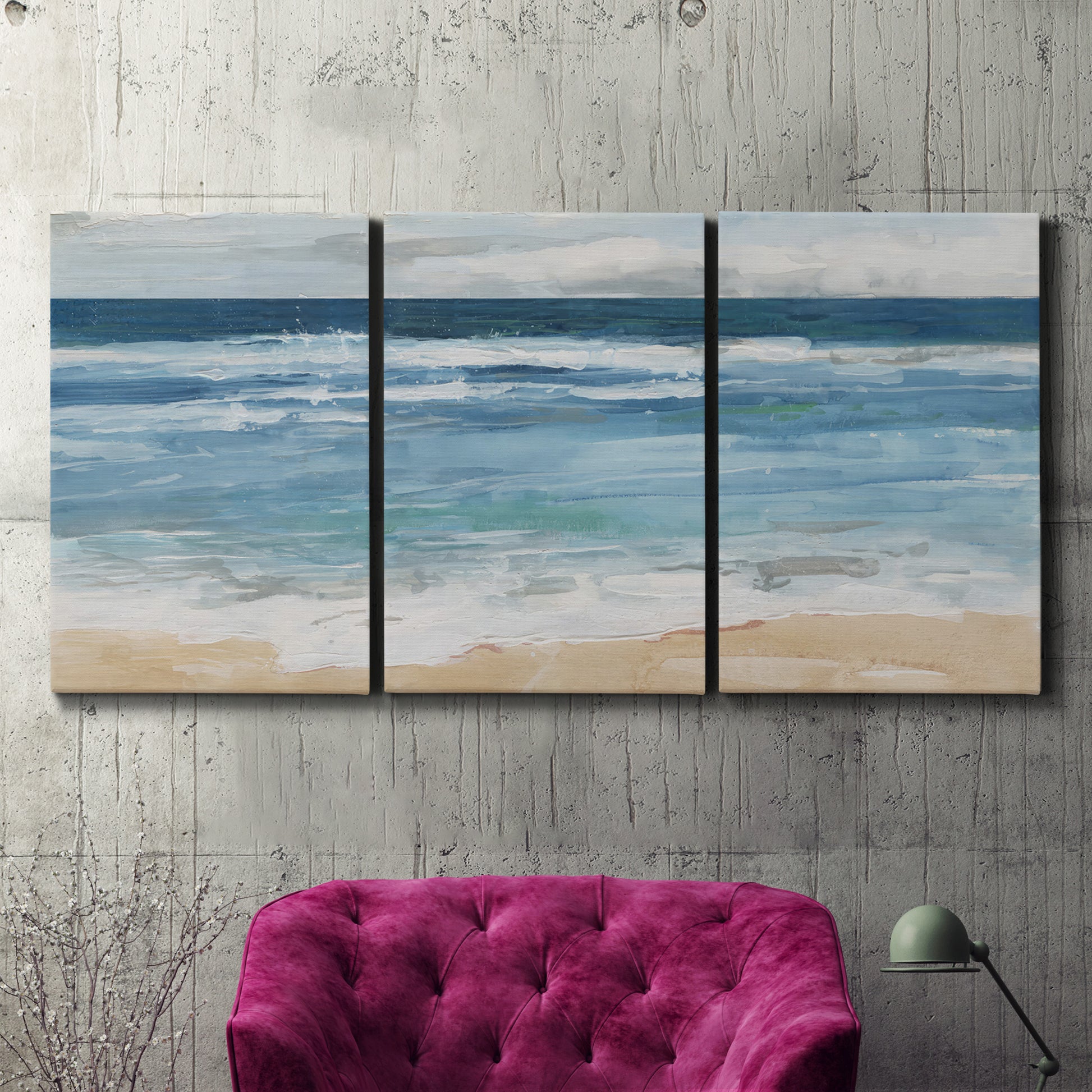 Three-panel canvas wall art featuring rolling ocean waves near shore, displayed in a living room above a suede accent chair.