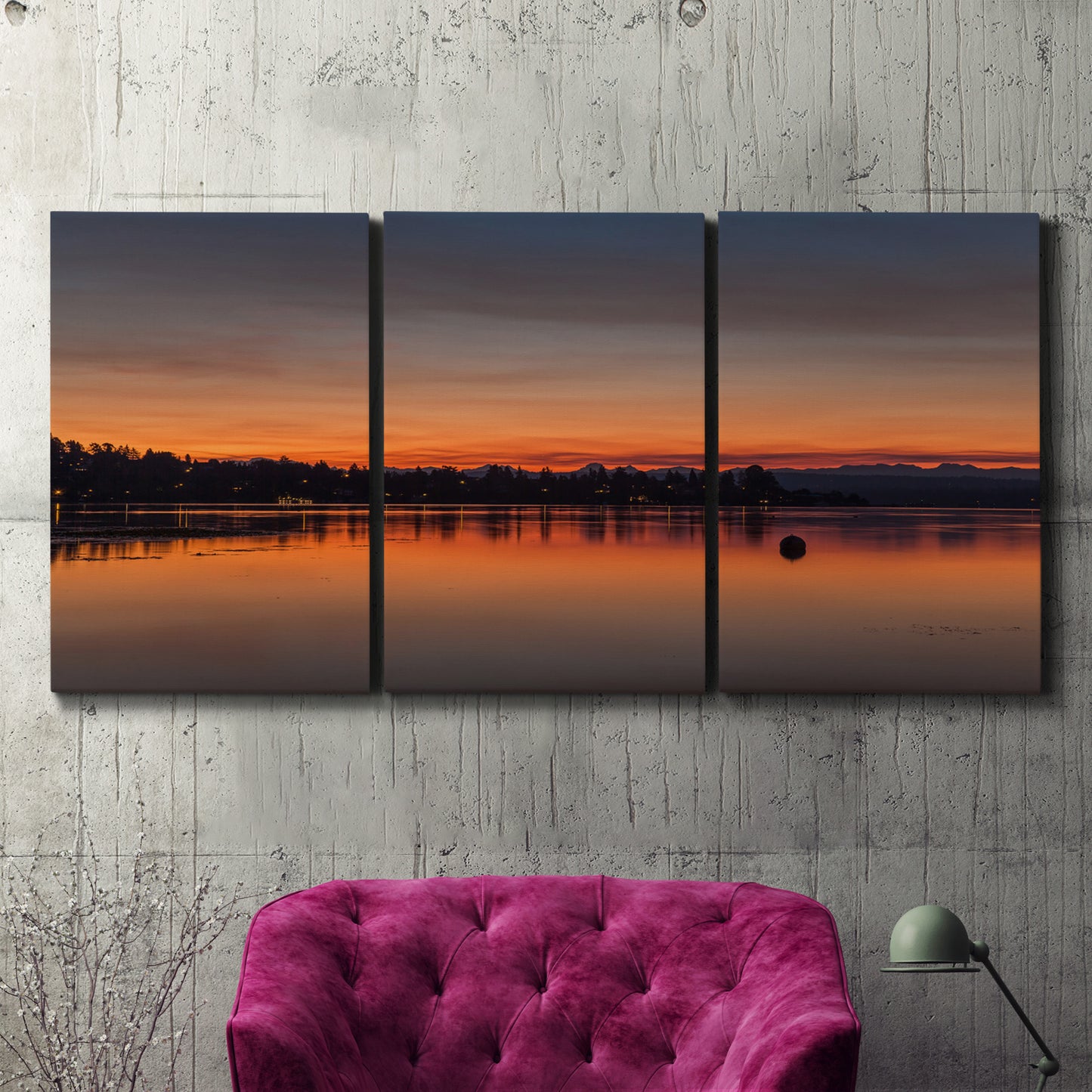 Three-panel canvas wall art featuring glowing sunset over water, displayed in a living room above a suede accent chair.