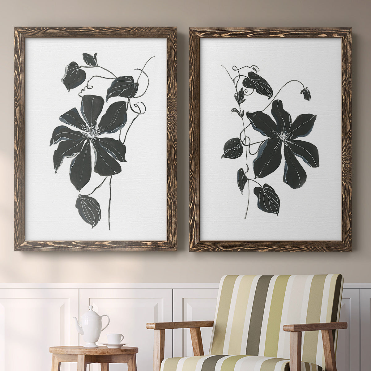 Set of two walnut barnwood framed canvas prints depicting two minimalist botanical prints featuring black leafy vine silhouettes above a sideboard in a cozy sitting room.
