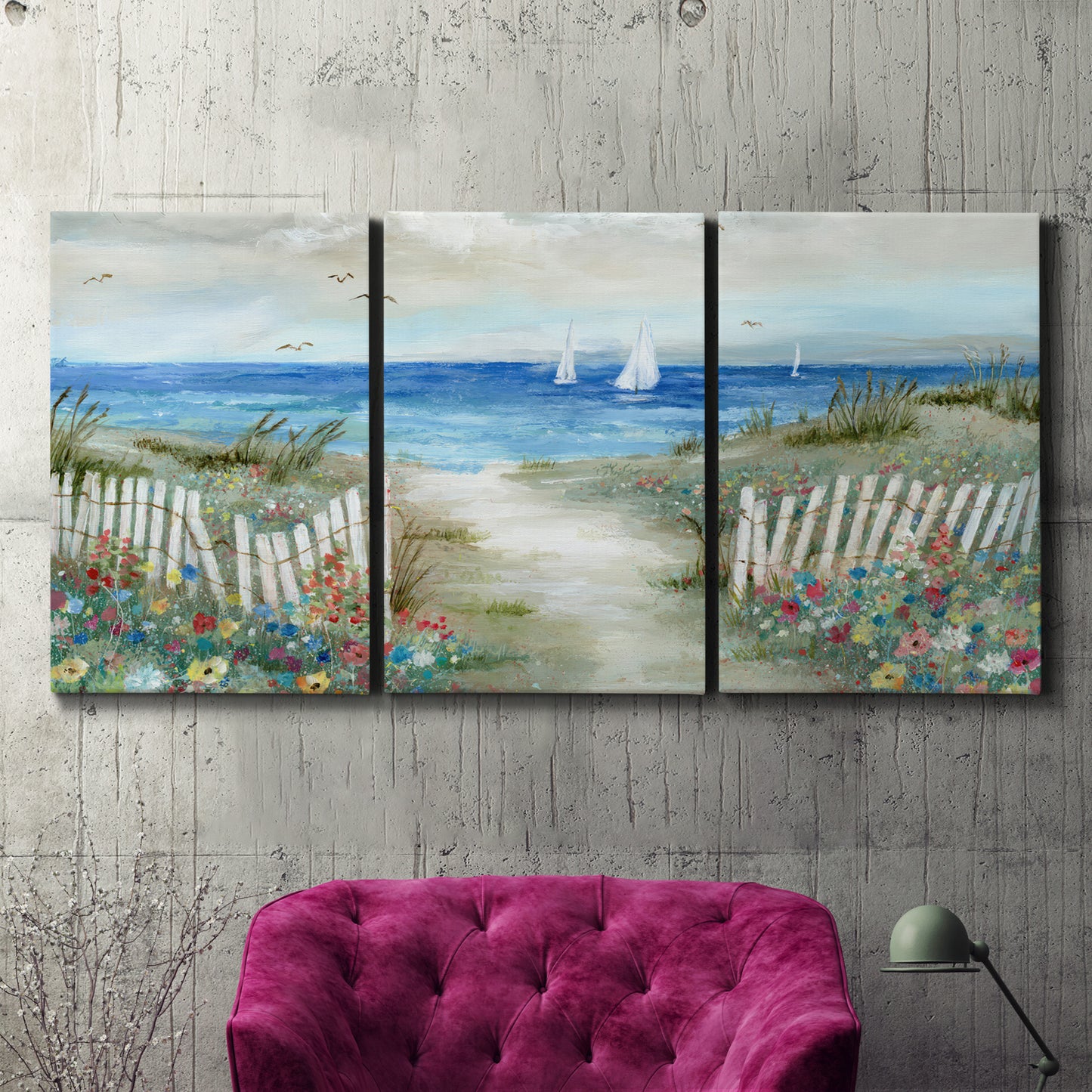Three-panel canvas wall art featuring lush coastal garden landscape, displayed in a living room above a suede accent chair.