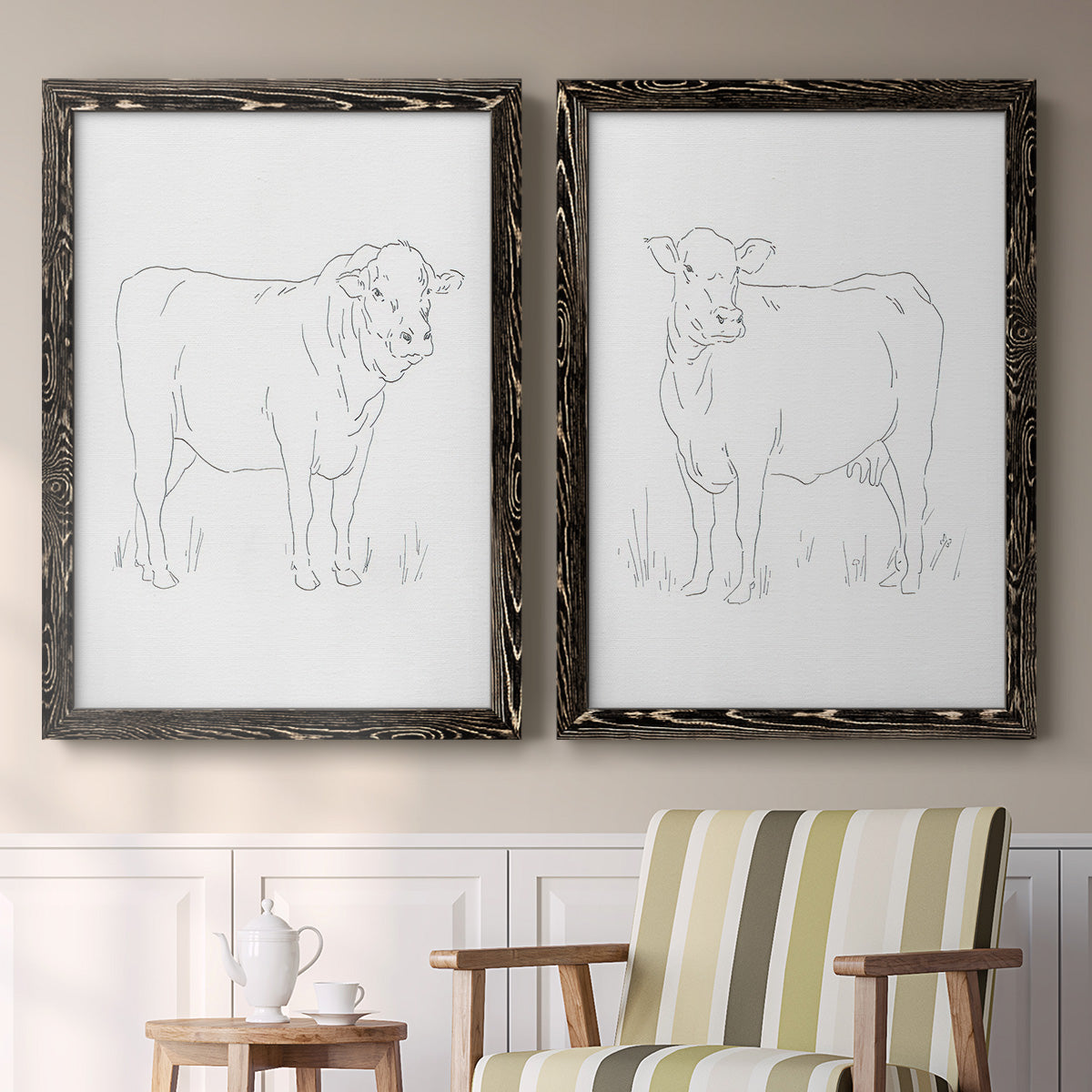 Set of two black barnwood framed canvas prints depicting two minimalist livestock sketches featuring simple contour drawings of standing cows above a sideboard in a cozy sitting room.