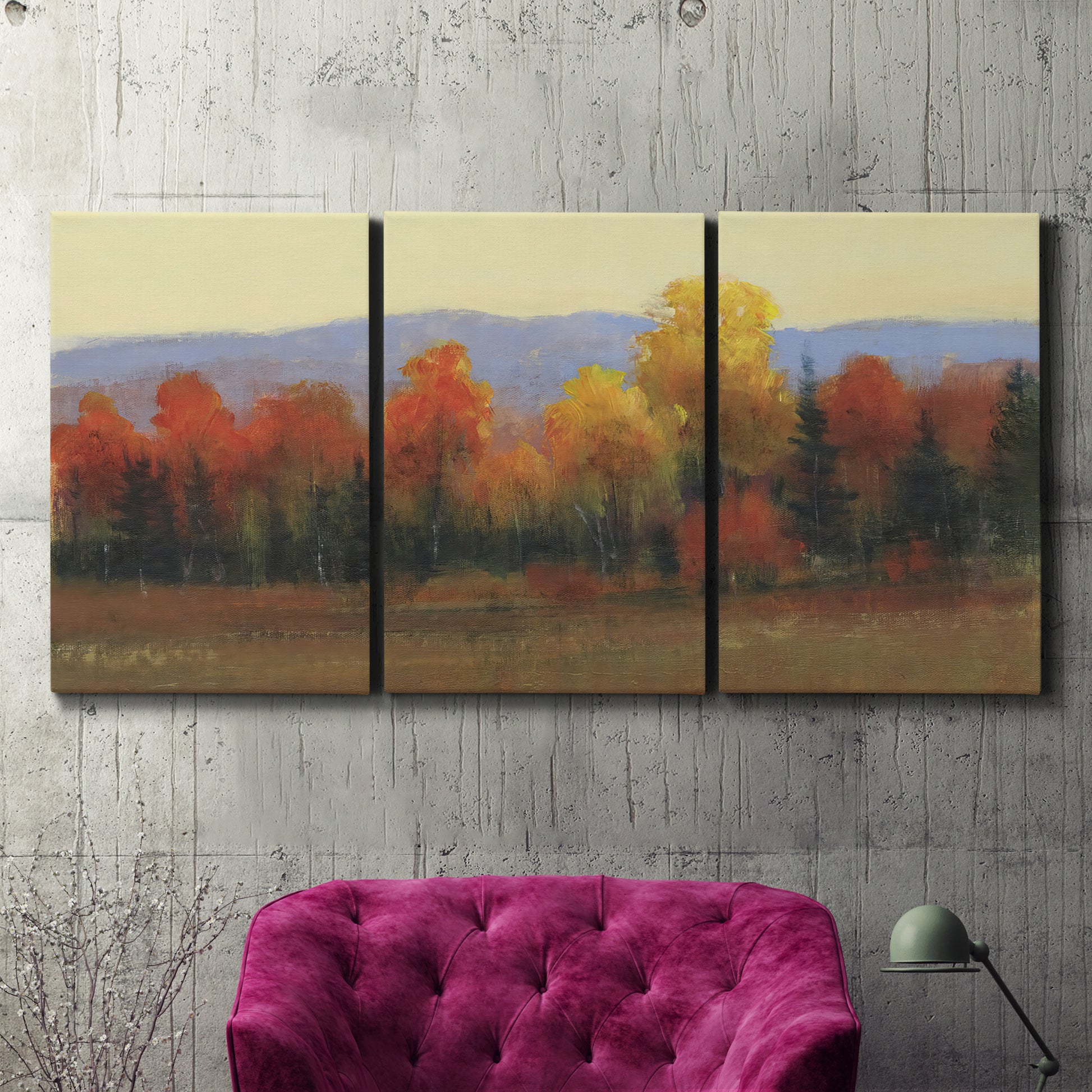 Three-panel canvas wall art featuring autumn landscape changing foliage, displayed in a living room above a suede accent chair.